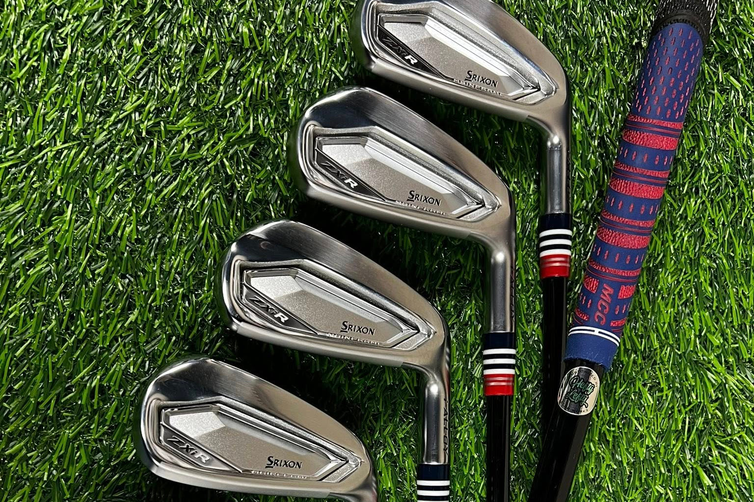 Set of Srixon golf clubs with a Hefty Lefty Club Works sticker on a grass background