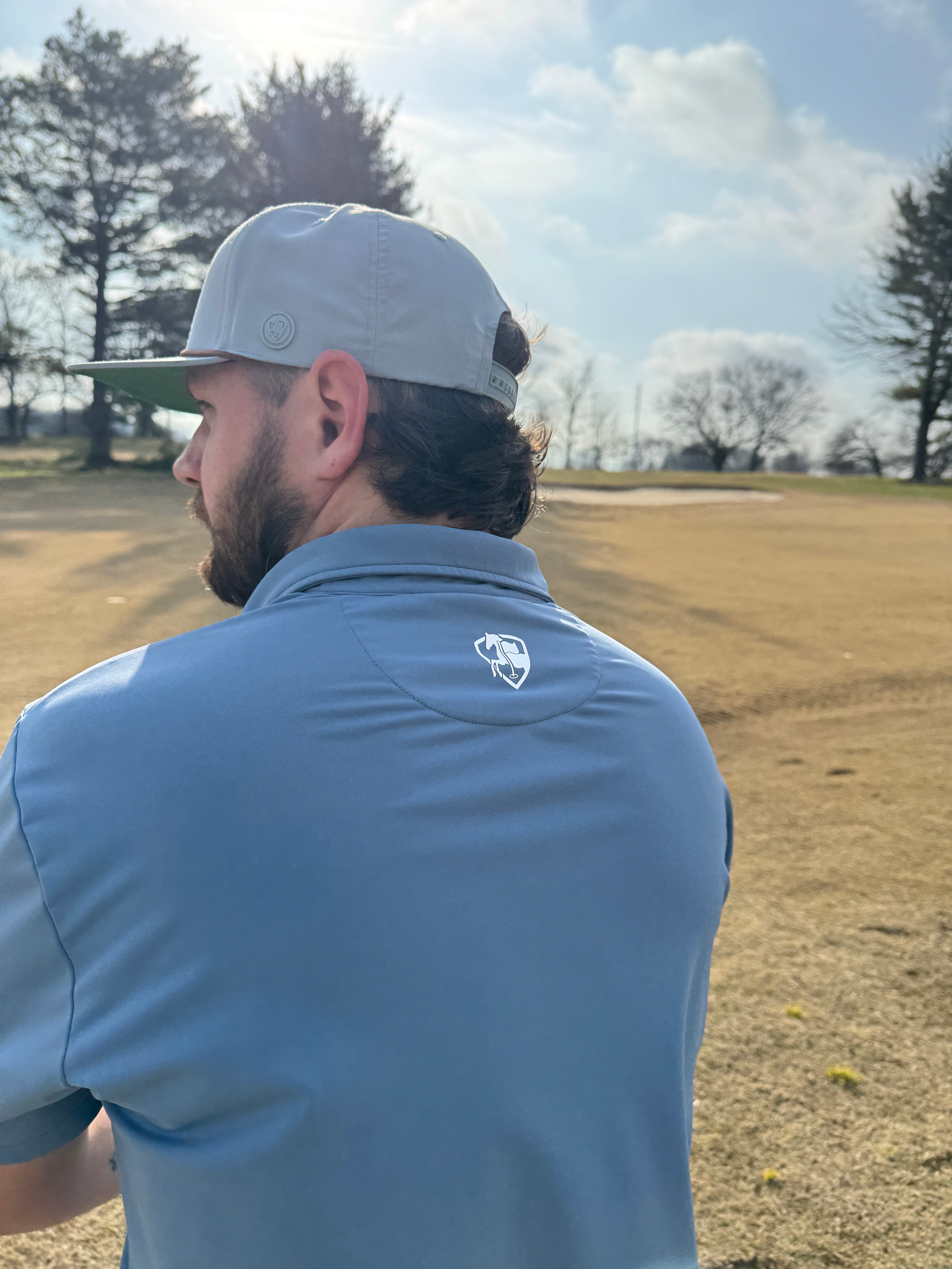 Man in a blue shirt and white cap on a golf course
